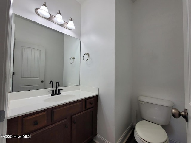 bathroom featuring baseboards, toilet, and vanity