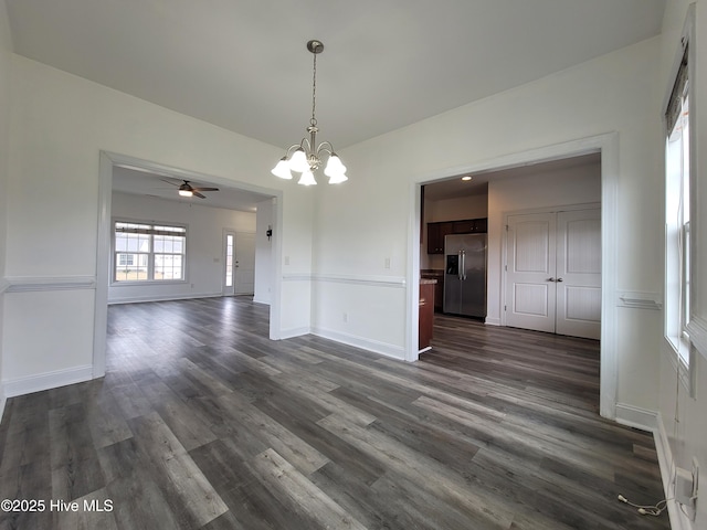 unfurnished dining area with dark wood-style floors, a chandelier, and baseboards