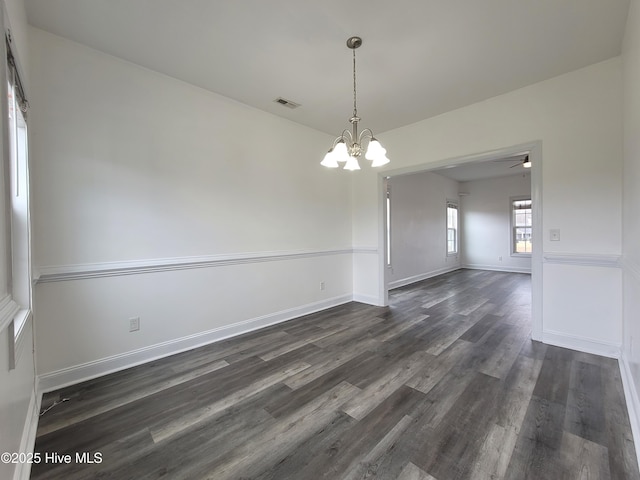 unfurnished room with visible vents, baseboards, an inviting chandelier, and dark wood-style flooring