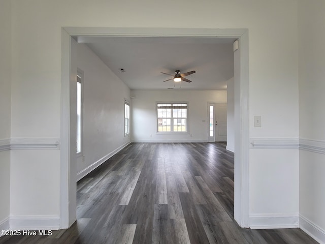 empty room featuring visible vents, baseboards, dark wood finished floors, and a ceiling fan