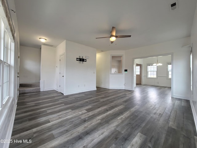 unfurnished living room featuring visible vents, baseboards, dark wood finished floors, and ceiling fan with notable chandelier