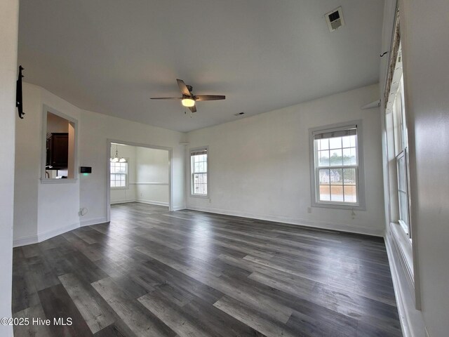 unfurnished living room featuring ceiling fan, visible vents, baseboards, and dark wood-style floors