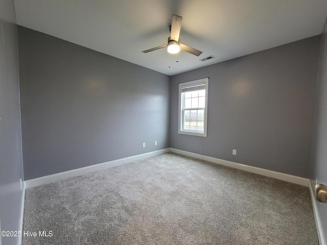 unfurnished room with carpet flooring, visible vents, a ceiling fan, and baseboards