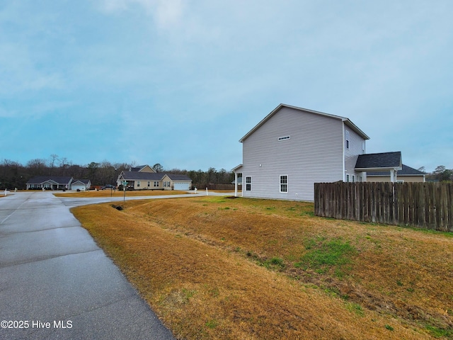 view of side of home featuring a lawn and fence