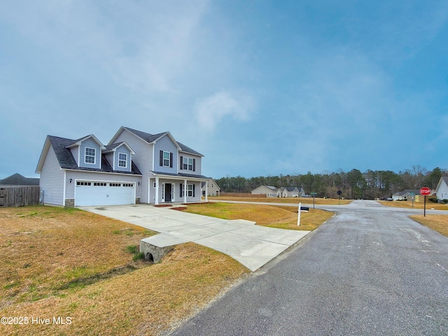 view of front of home with a porch, fence, concrete driveway, an attached garage, and a front yard