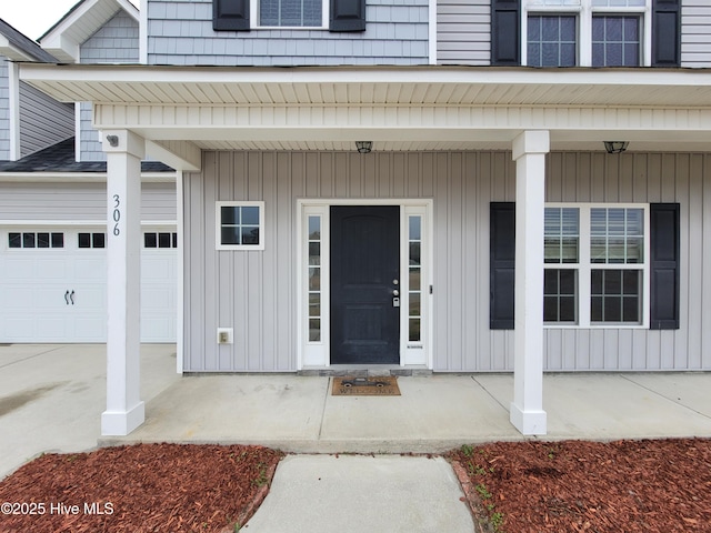 view of exterior entry featuring a porch and a garage