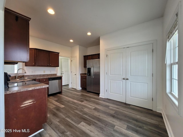 kitchen featuring dark brown cabinetry, dark wood-style floors, stainless steel appliances, and a sink