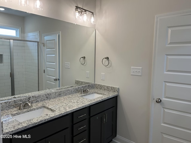 full bath with double vanity, a tile shower, and baseboards