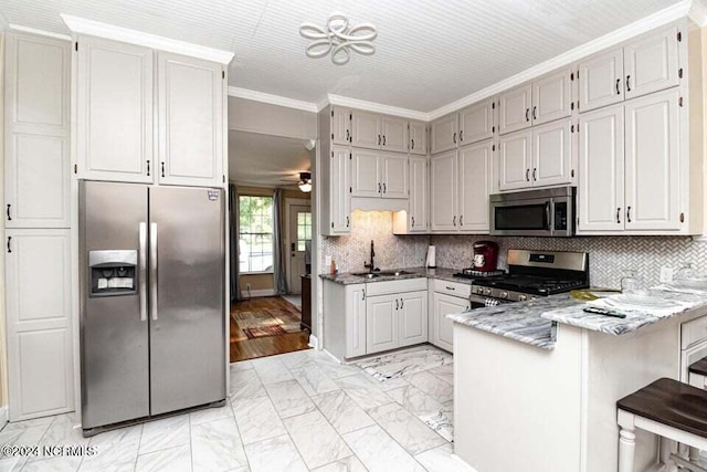 kitchen with ornamental molding, a peninsula, marble finish floor, stainless steel appliances, and a sink