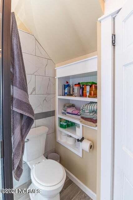 bathroom with tile walls, toilet, and wood finished floors