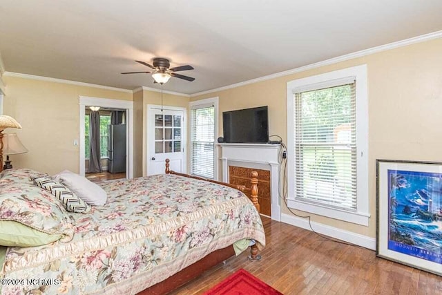 bedroom with crown molding, multiple windows, a fireplace, and wood finished floors