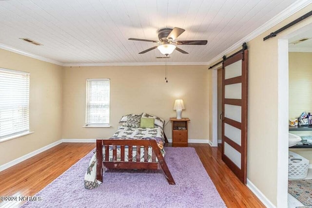 bedroom featuring ornamental molding, wood finished floors, visible vents, and a barn door