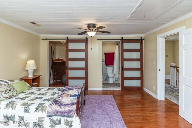 bedroom with a barn door, wood finished floors, baseboards, ornamental molding, and attic access