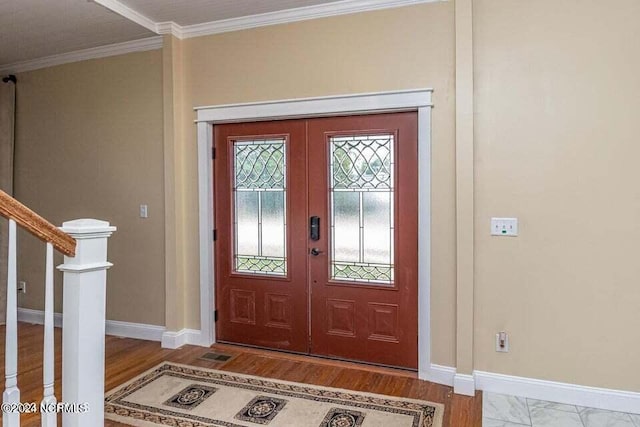 entrance foyer featuring ornamental molding, stairway, wood finished floors, and baseboards