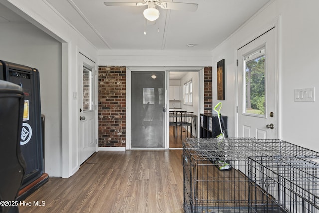 interior space with brick wall, ceiling fan, and wood finished floors