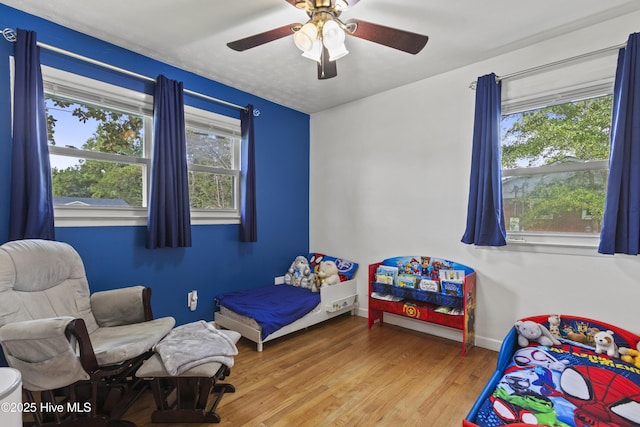 bedroom with ceiling fan, wood finished floors, and baseboards