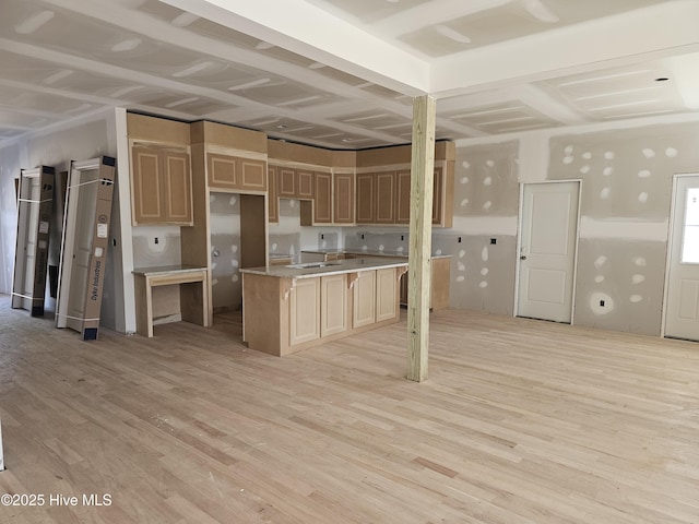 kitchen featuring light wood-type flooring, a center island, light countertops, and light brown cabinetry