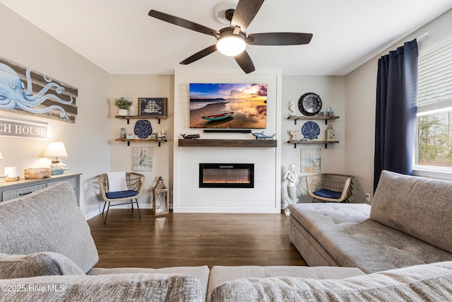 living room with a large fireplace, ceiling fan, wood finished floors, and baseboards