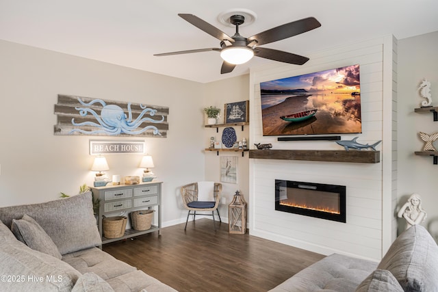 living area featuring a ceiling fan, a fireplace, baseboards, and wood finished floors