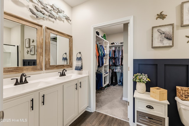 bathroom with double vanity, wood finished floors, a sink, and toilet