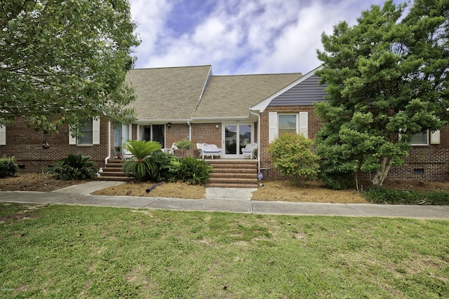 view of front of home featuring crawl space, brick siding, a front lawn, and roof with shingles