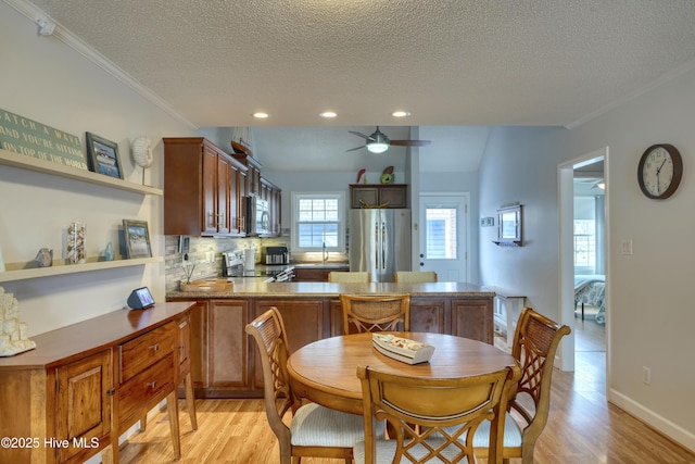 dining area featuring crown molding, a textured ceiling, light wood finished floors, and ceiling fan