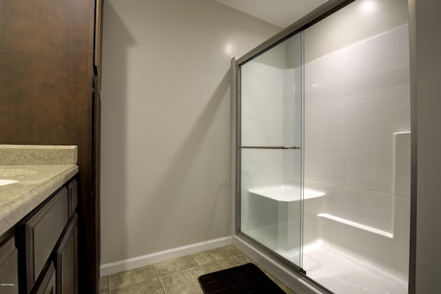 bathroom featuring a stall shower, vanity, baseboards, and tile patterned floors