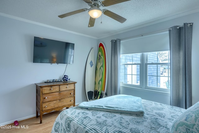 bedroom with a textured ceiling, ceiling fan, wood finished floors, baseboards, and ornamental molding