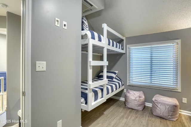 bedroom with a textured ceiling, baseboards, and wood finished floors