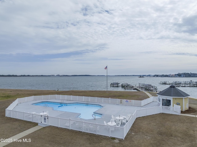 community pool with a patio, a boat dock, a water view, and a fenced backyard