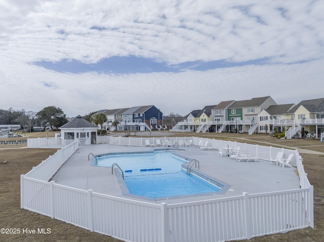 pool featuring a gazebo, a patio, fence, and a residential view