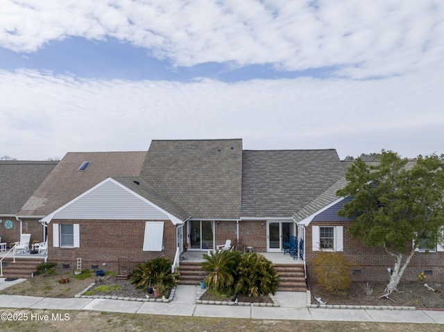 view of front of property featuring a shingled roof, crawl space, and brick siding