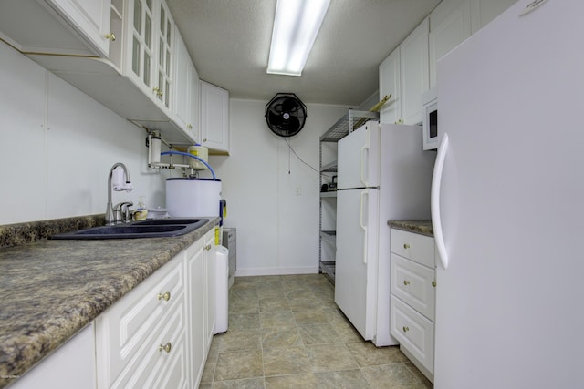 kitchen with glass insert cabinets, freestanding refrigerator, white cabinets, and a sink