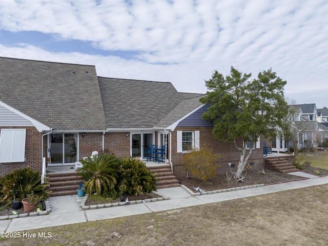 view of front of property with brick siding and a shingled roof