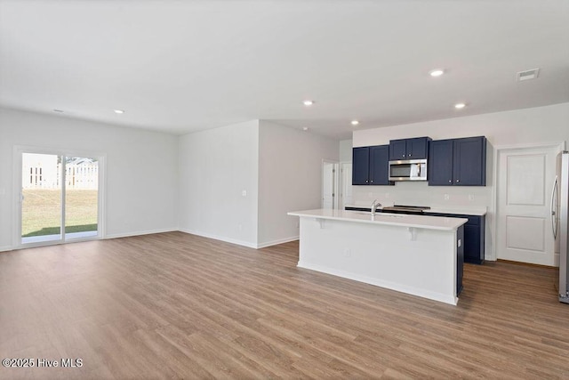 kitchen featuring stainless steel appliances, light wood-type flooring, light countertops, and visible vents