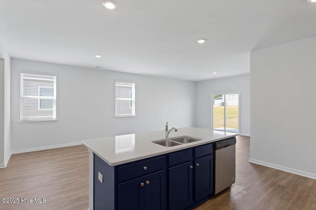 kitchen with open floor plan, wood finished floors, a sink, light countertops, and stainless steel dishwasher