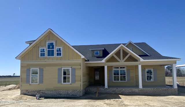 view of front of property featuring covered porch, board and batten siding, and roof with shingles