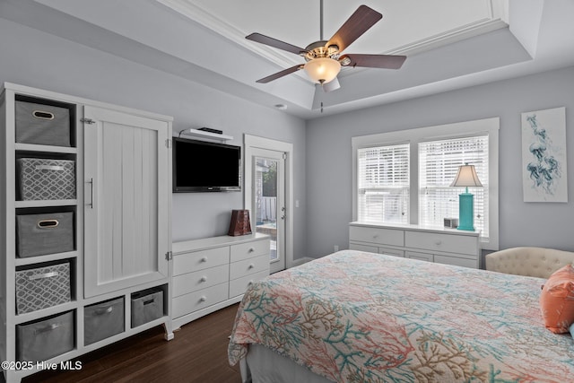 bedroom featuring ceiling fan, a tray ceiling, dark wood finished floors, and access to exterior