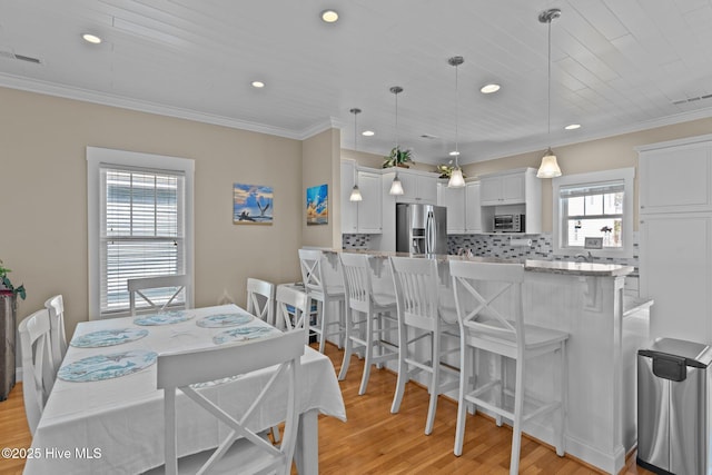 dining room featuring visible vents, light wood finished floors, and ornamental molding