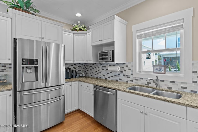 kitchen with ornamental molding, appliances with stainless steel finishes, white cabinetry, and a sink