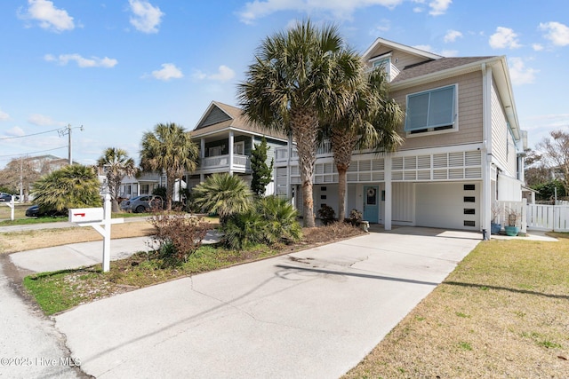 coastal home with concrete driveway, an attached garage, and fence