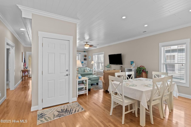 dining space featuring light wood finished floors, a ceiling fan, baseboards, and ornamental molding