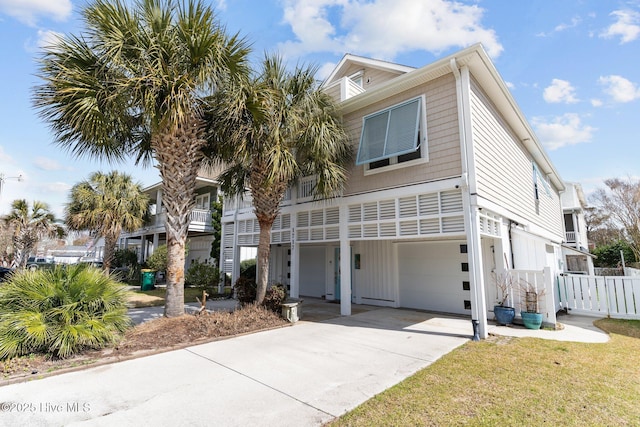 view of front of house with an attached garage, concrete driveway, and fence