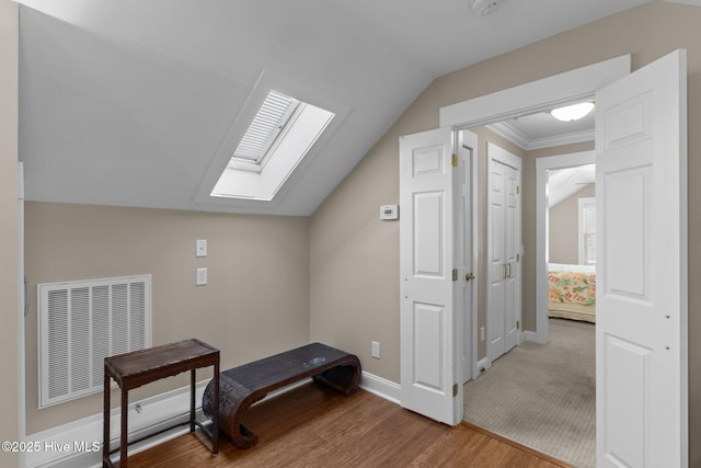 additional living space with visible vents, lofted ceiling with skylight, baseboards, and wood finished floors