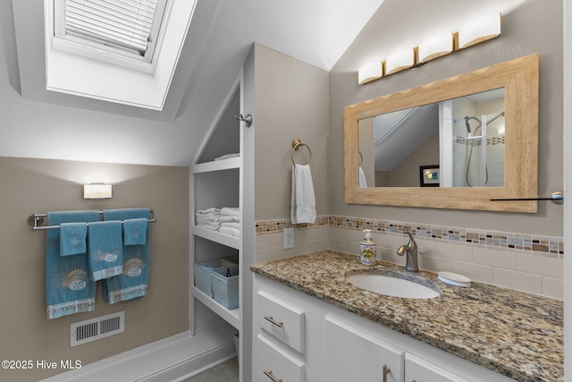 bathroom with lofted ceiling with skylight, visible vents, and backsplash