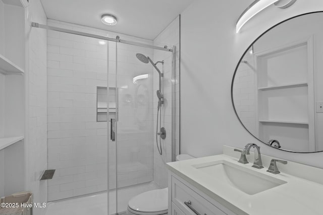 bathroom featuring a shower stall, toilet, and vanity