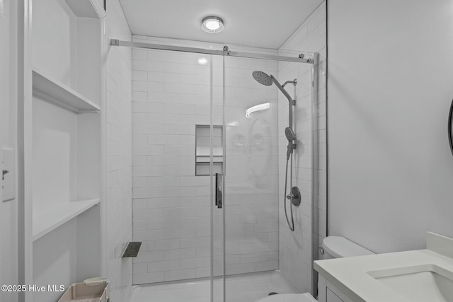 bathroom featuring vanity, a shower stall, and toilet