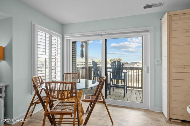 dining space featuring light wood-type flooring, visible vents, and baseboards