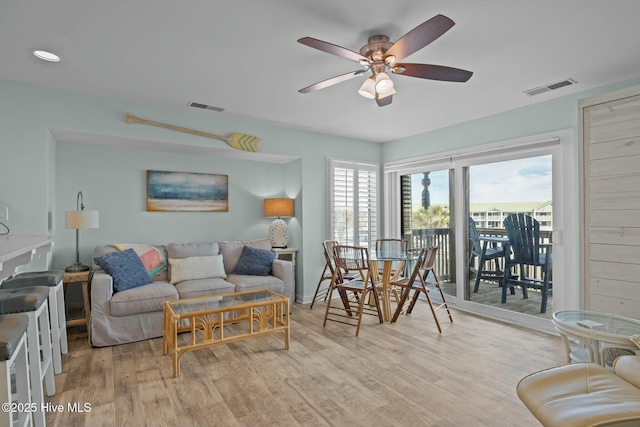 living area with light wood-style floors, visible vents, and a ceiling fan