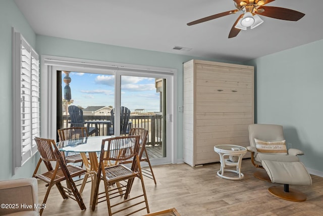 dining space featuring light wood finished floors, ceiling fan, visible vents, and baseboards